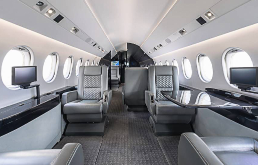 fig-air_9-falcon-900-ex_p3.2 Interior photo showing a straight-on view of the cabin of FIG Air’s Falcon 900 EX jet. Luxurious grey jet interior seating and carpet. Workstations in jet with monitors.